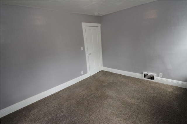 empty room featuring dark colored carpet, baseboards, and visible vents