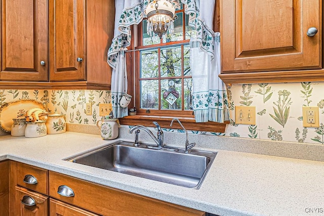 kitchen with a sink, an inviting chandelier, and brown cabinetry