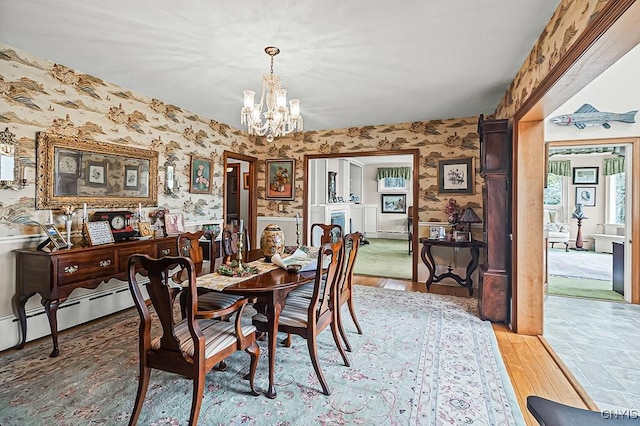 dining room with wallpapered walls, a chandelier, light wood-style flooring, and a wainscoted wall