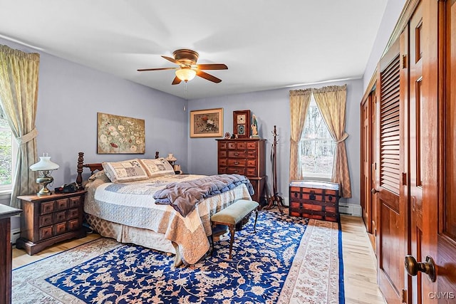 bedroom with a closet, light wood-type flooring, a baseboard radiator, and ceiling fan