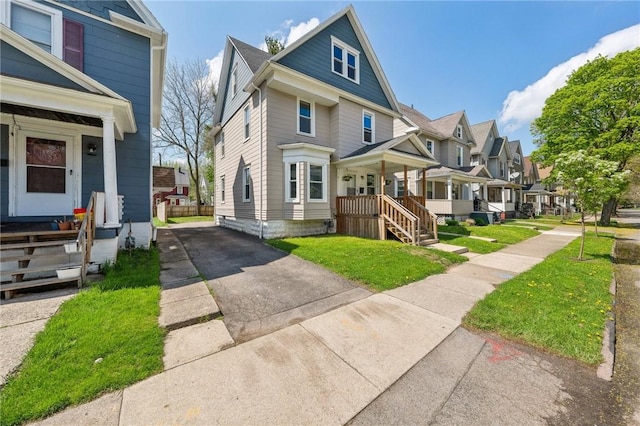 american foursquare style home with a porch, driveway, a front lawn, and a residential view
