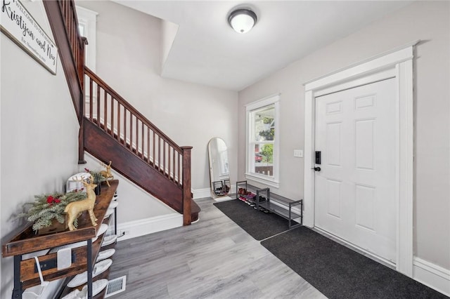 foyer entrance featuring stairway, visible vents, and wood finished floors