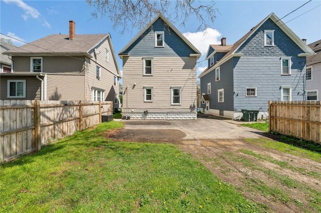 rear view of house featuring a patio area, fence, and a lawn