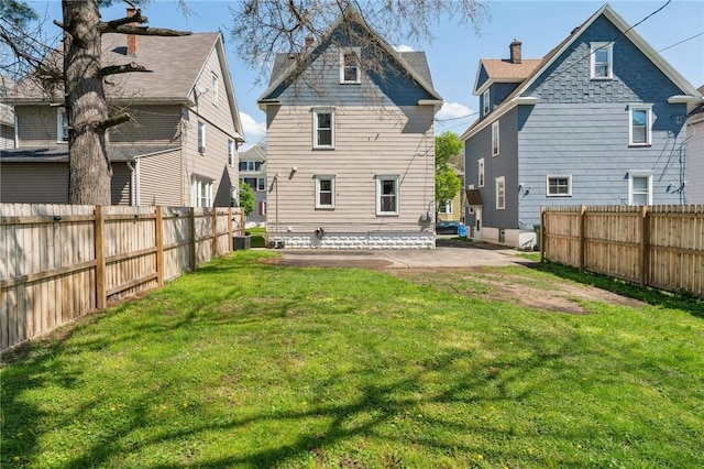 back of property with a yard, a patio area, and a fenced backyard
