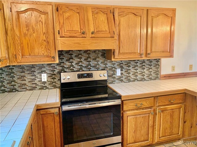 5048 State Route 28, Webb, NY 13420 - kitchen with backsplash, tile counters, and electric stove