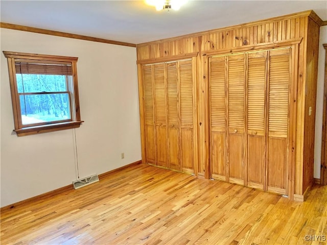 5048 State Route 28, Webb, NY 13420 - unfurnished bedroom with multiple closets, visible vents, crown molding, light wood-style flooring, and baseboards