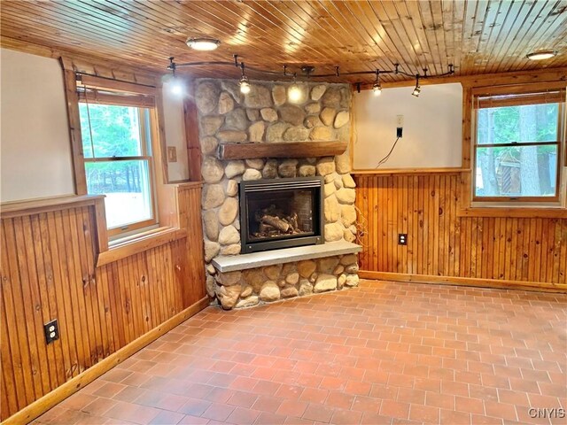 5048 State Route 28, Webb, NY 13420 - unfurnished living room with a stone fireplace, a wainscoted wall, track lighting, and wood walls