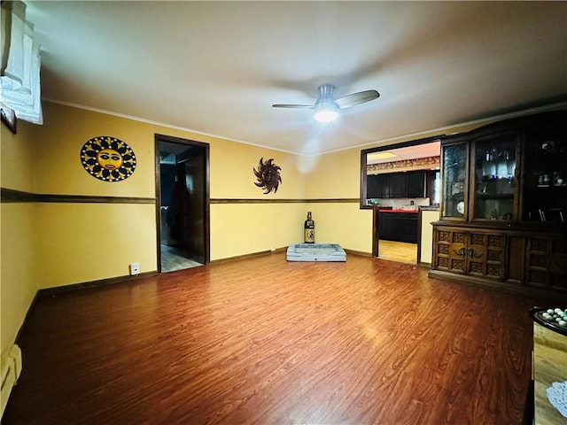 121 E William St, Bath, NY 14810 - unfurnished living room featuring wood finished floors, a ceiling fan, crown molding, baseboards, and a baseboard radiator