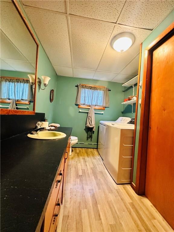 121 E William St, Bath, NY 14810 - laundry area featuring a baseboard radiator, a sink, wood finished floors, laundry area, and washer and clothes dryer