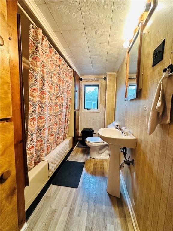 121 E William St, Bath, NY 14810 - bathroom with wooden walls, toilet, shower / bath combo with shower curtain, and wood finished floors
