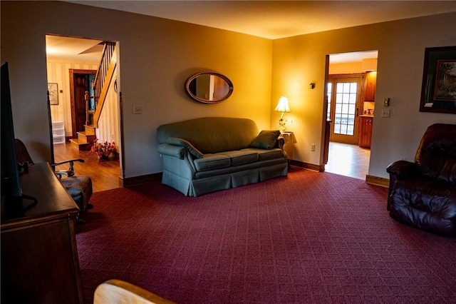 carpeted living room featuring stairway and baseboards