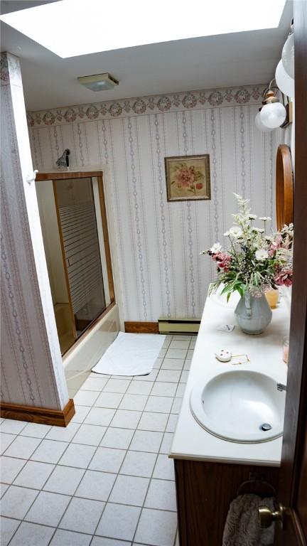 full bath with vanity, a skylight, bath / shower combo with glass door, and wallpapered walls