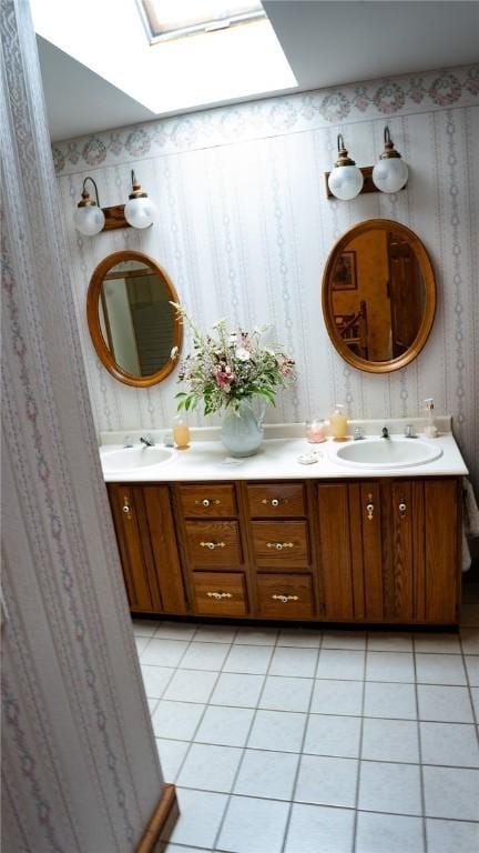 bathroom with double vanity, a sink, wallpapered walls, a skylight, and tile patterned flooring