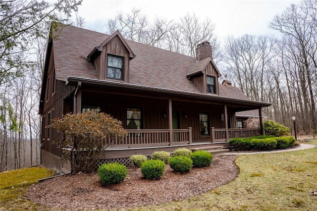 view of front of property featuring a chimney, board and batten siding, a porch, and a front yard