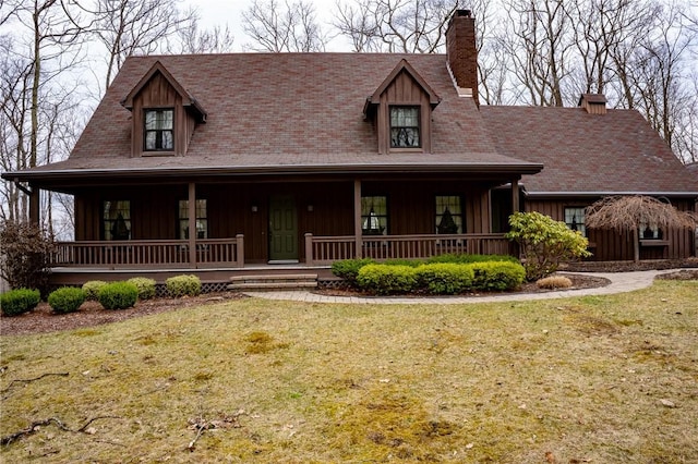 view of front of property featuring a chimney, board and batten siding, covered porch, and a front yard