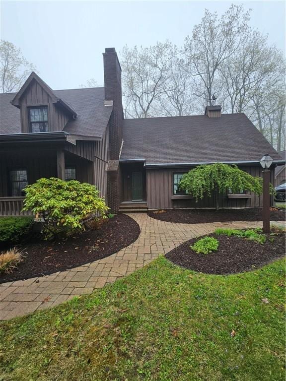 view of front of property with roof with shingles, a chimney, and board and batten siding