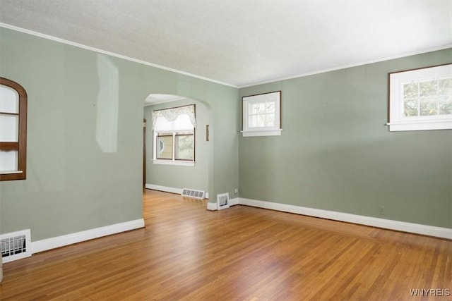 empty room with ornamental molding, arched walkways, baseboards, and visible vents