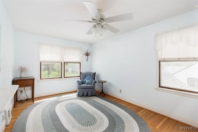 sitting room featuring light wood finished floors, baseboards, and a ceiling fan