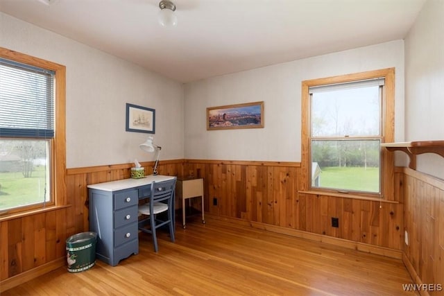 office featuring light wood-type flooring, wooden walls, and a wainscoted wall