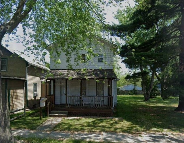 back of property featuring covered porch and a yard