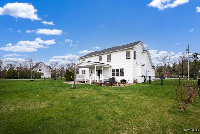 rear view of house with a yard, fence, and a porch