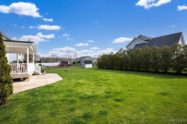 view of yard with a patio area, an outdoor structure, a deck, and a storage unit