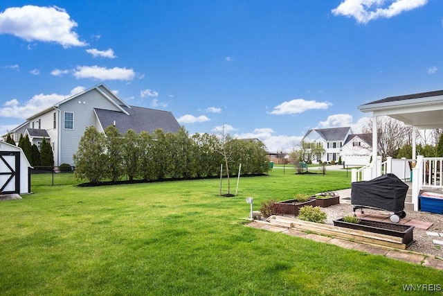 view of yard with a storage shed, a garden, an outdoor structure, and fence