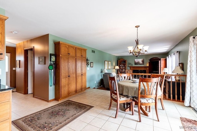 dining room with an inviting chandelier, light tile patterned floors, visible vents, and a fireplace