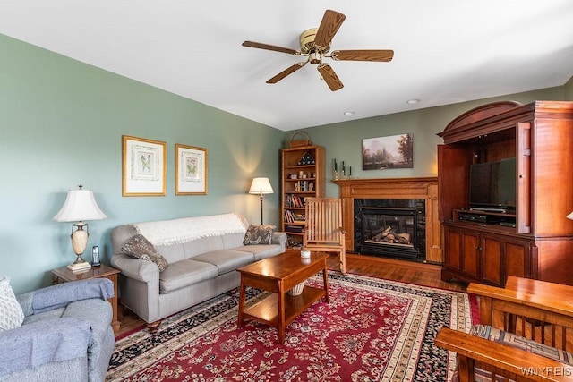 living room featuring a fireplace, ceiling fan, and wood finished floors