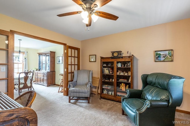 sitting room featuring carpet, baseboards, and a ceiling fan