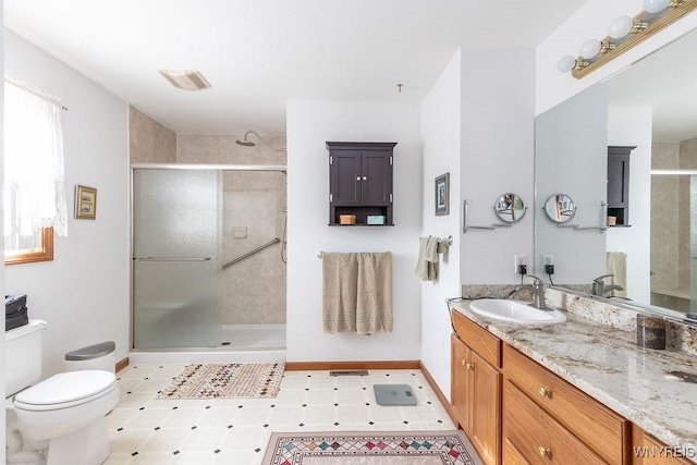 bathroom featuring baseboards, toilet, visible vents, a shower stall, and vanity