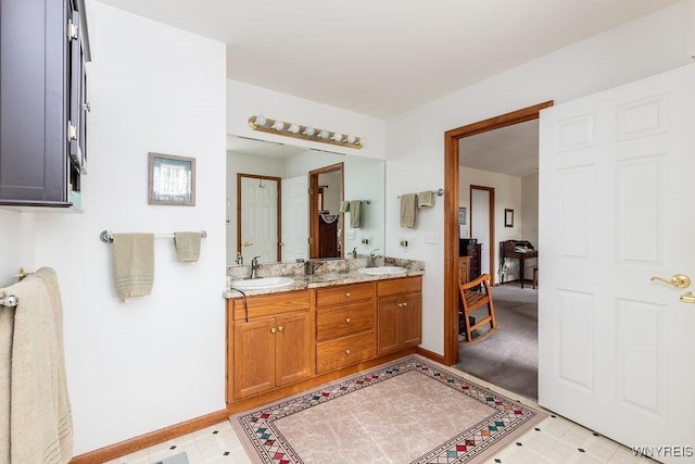 full bathroom with baseboards, double vanity, and a sink