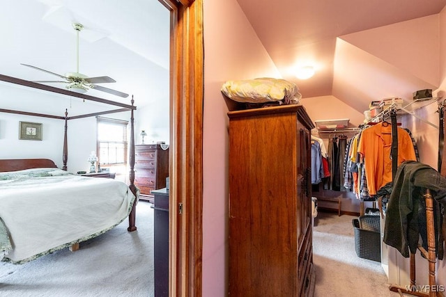 spacious closet with vaulted ceiling, light colored carpet, and a ceiling fan