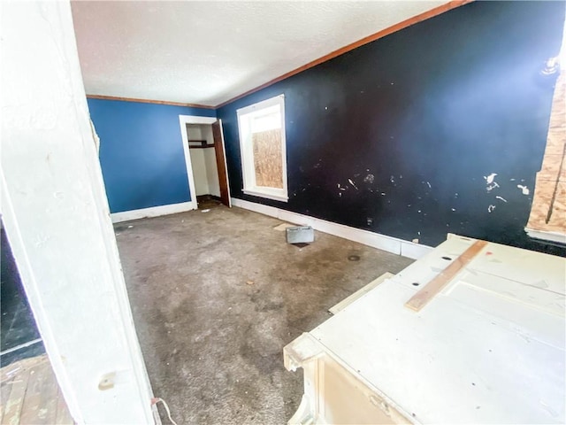 spare room featuring concrete flooring, a textured ceiling, baseboards, and ornamental molding