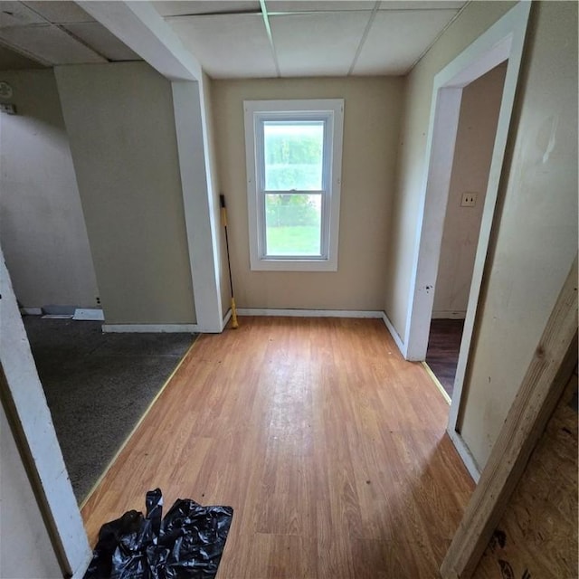 unfurnished room featuring a drop ceiling, baseboards, and wood finished floors