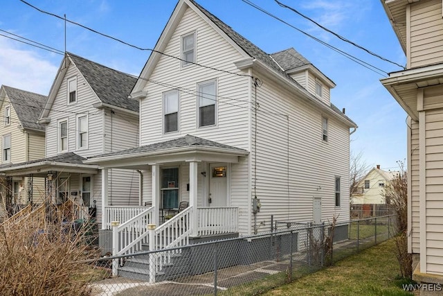 view of front facade featuring covered porch, roof with shingles, and fence private yard