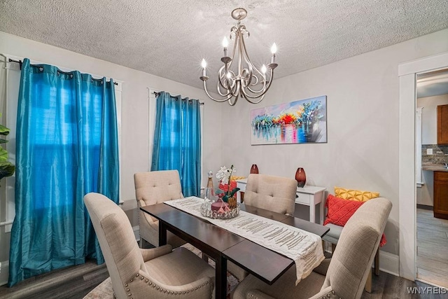 dining space with a chandelier, a textured ceiling, and wood finished floors