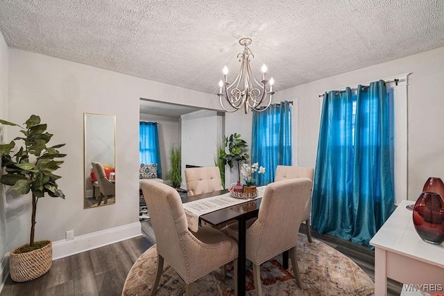 dining area featuring a textured ceiling, a chandelier, wood finished floors, and baseboards