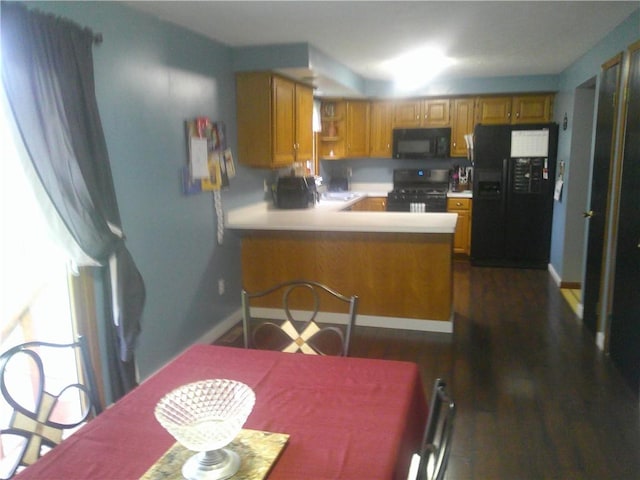 kitchen featuring black appliances, light countertops, a peninsula, and brown cabinets