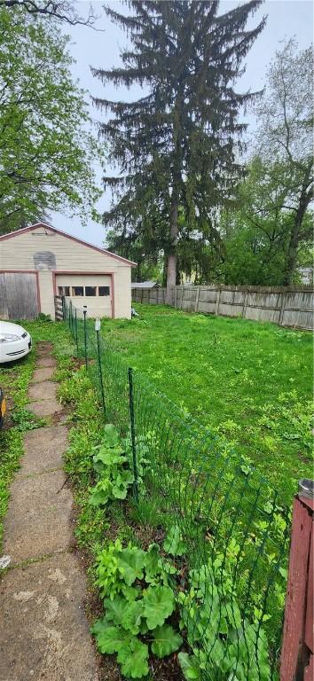 view of yard featuring a fenced backyard, an outdoor structure, and a detached garage