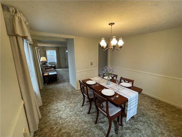 dining area featuring carpet, a textured ceiling, and a chandelier