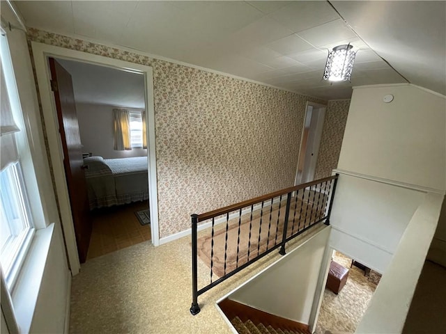 corridor featuring an upstairs landing and wallpapered walls