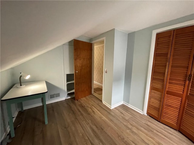 bonus room featuring vaulted ceiling, baseboards, visible vents, and wood finished floors