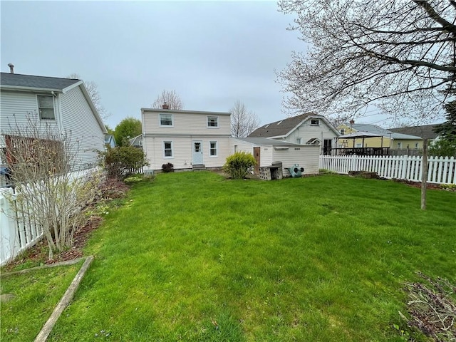 rear view of property with a chimney, fence, and a lawn