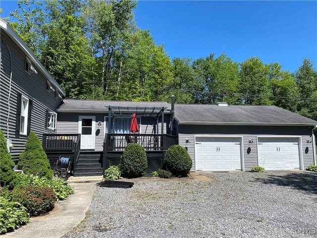 view of front of house with gravel driveway, a wooden deck, roof with shingles, and an attached garage