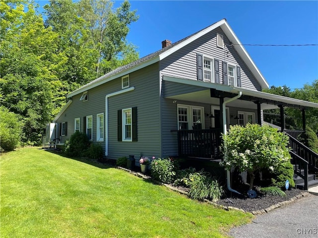 view of property exterior with a yard, stairway, a chimney, and a porch