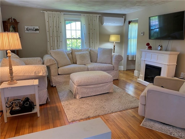 living room with baseboards, a glass covered fireplace, wood-type flooring, and a wall mounted AC