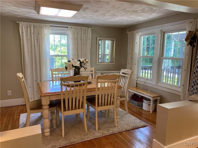 dining space with baseboards and wood-type flooring