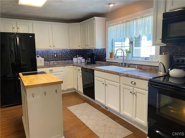 kitchen with wood counters, black appliances, white cabinets, and a sink