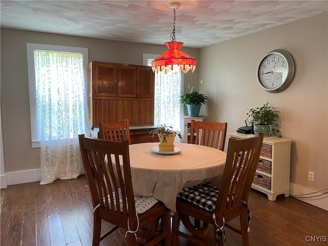dining area featuring dark wood-style flooring and baseboards